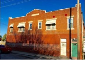 Tulsa apartment for rent - A red brick building with a green door and a tree in front.