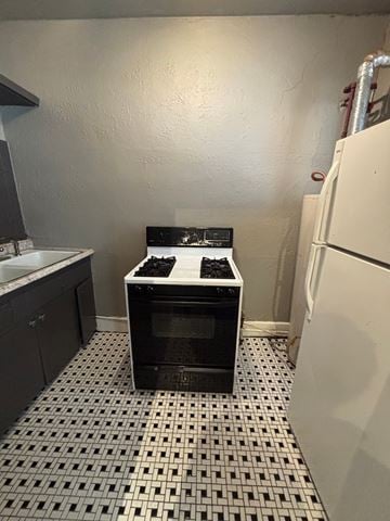 Tulsa apartment for rent - A black and white oven in a kitchen with a white tiled floor.