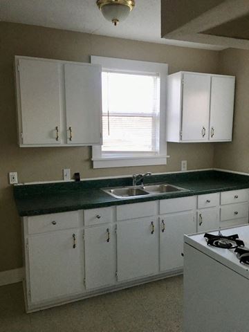 Tulsa apartment for rent - a kitchen with white cabinets and a sink and a window