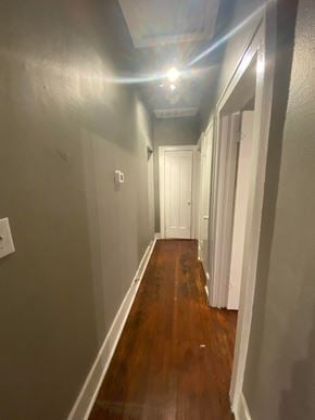 Tulsa house for rent - a hallway with a hard wood floor and grey walls and a white door
