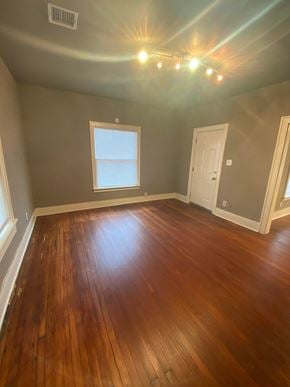 Tulsa house for rent - an empty living room with wooden floors and a window