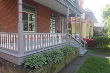 Pittsburgh apartment for rent - A red brick house with a white porch.