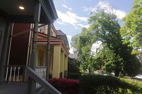 Pittsburgh apartment for rent - A yellow house with a porch and a tree in front.