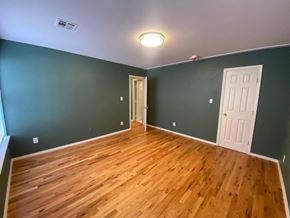 Tulsa apartment for rent - a living room with green walls and a wooden floor and a door