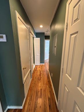 Tulsa apartment for rent - A long hallway with white doors and green walls.