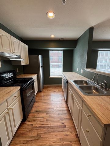 Tulsa apartment for rent - A kitchen with wooden floors and white cabinets.