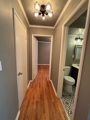 Tulsa apartment for rent - A hallway with a wooden floor and a chandelier.