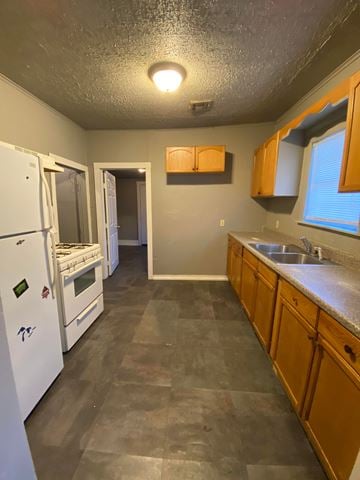 Tulsa house for rent - A kitchen with a white fridge, wooden cabinets, and a sink.