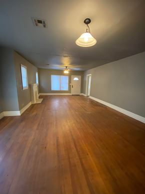 Tulsa house for rent - A room with wooden floors and a light hanging from the ceiling.