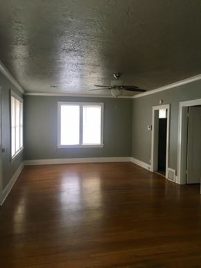 Tulsa house for rent - an empty living room with wood floors and a ceiling fan