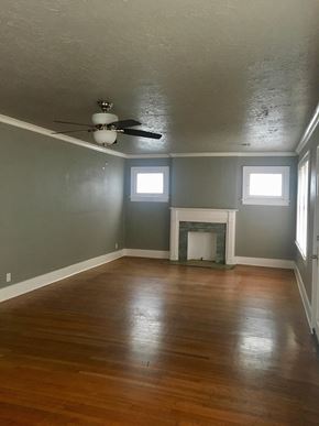 Tulsa house for rent - an empty living room with a ceiling fan and a fireplace