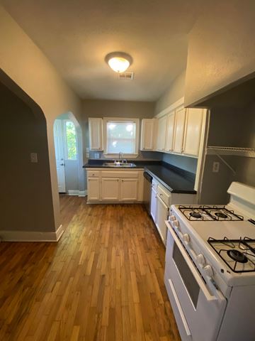 Tulsa house for rent - a kitchen with a stove and a wooden floor