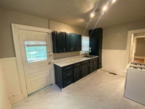 Tulsa house for rent - an empty kitchen with black cabinets and a door