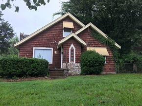 Tulsa house for rent - a small red brick house with a grassy yard and trees