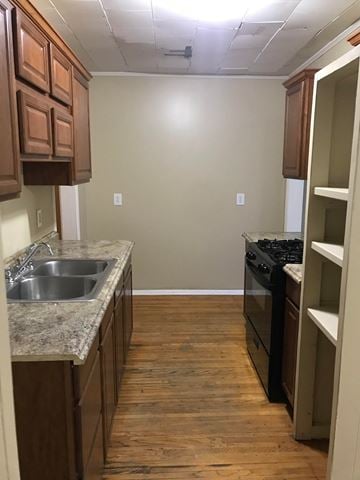 Tulsa house for rent - a kitchen with wooden floors and a sink and a stove