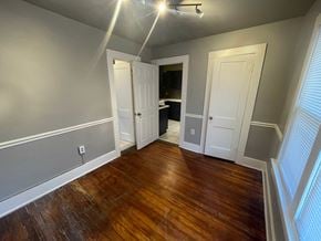 Tulsa house for rent - a living room with wooden floors and a door into a bathroom