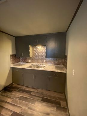 Tulsa apartment for rent - an empty kitchen with dark cabinets and a sink