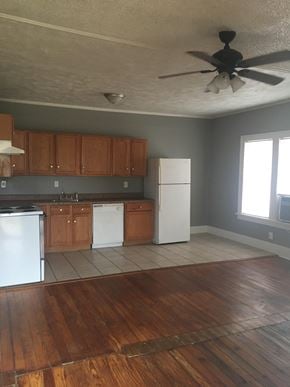 Tulsa house for rent - an empty kitchen with a ceiling fan and wooden floors