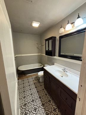 Tulsa house for rent - A bathroom with a patterned floor and a bathtub.