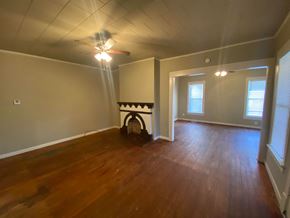 Tulsa house for rent - an empty living room with a fireplace and wooden floors