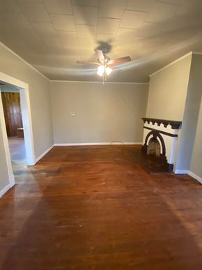 Tulsa house for rent - an empty living room with a fireplace and a ceiling fan