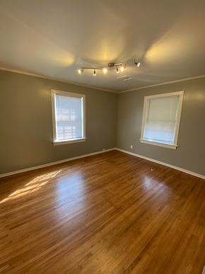 Tulsa house for rent - an empty living room with wood floors and two windows