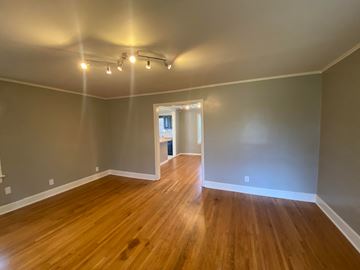 Tulsa house for rent - an empty living room with wood floors and grey walls