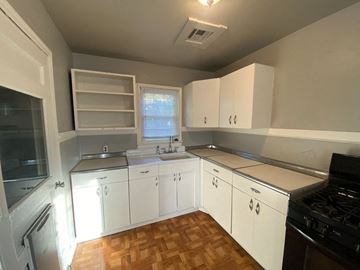Tulsa house for rent - a kitchen with white cabinets and a wood floor