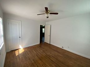 Tulsa house for rent - an empty living room with wood floors and a ceiling fan