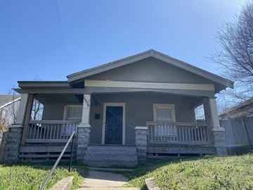Tulsa house for rent - A house with a grey front porch and a black door.