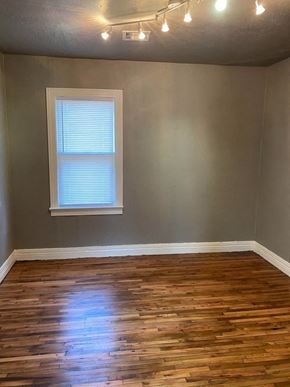 Tulsa house for rent - an empty room with wooden floors and a window