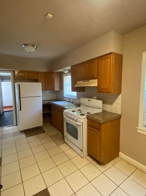 Tulsa house for rent - an empty kitchen with white appliances and wooden cabinets