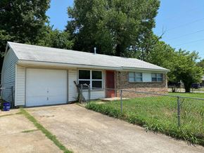 Tulsa house for rent - a small brick house with a white garage and a chain link fence