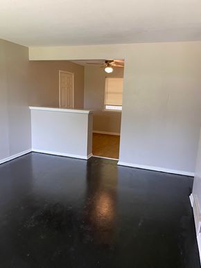 Tulsa house for rent - an empty living room with white walls and a black floor