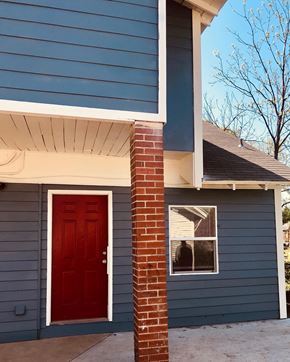 Tulsa house for rent - a red door on a blue house with a brick pillar