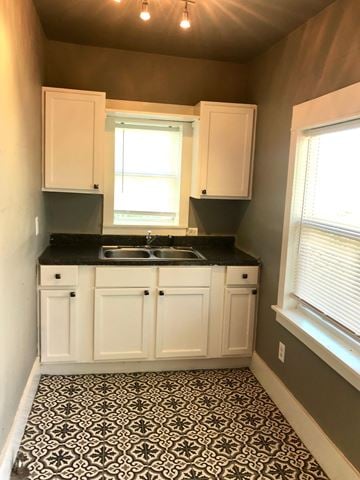 Tulsa house for rent - a small kitchen with white cabinets and a black and white tile floor