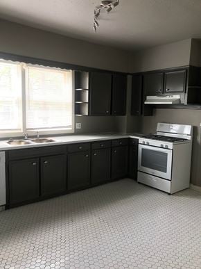 Tulsa house for rent - an empty kitchen with black cabinets and a stove and a window