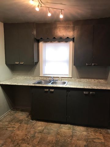 Tulsa house for rent - a kitchen with dark cabinets and a window and a sink