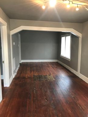 Tulsa house for rent - a living room with wood floors and gray walls and a window