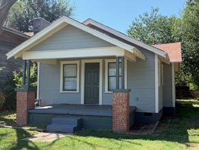 Tulsa house for rent - A small house with a grey siding and a brick pillar.