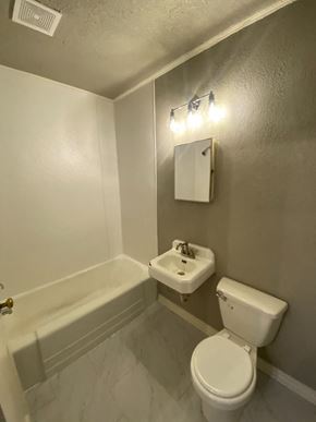 Tulsa house for rent - A white toilet sits next to a sink in a bathroom.
