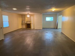 Tulsa house for rent - an empty living room with tile floors and a fireplace
