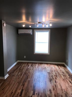 Tulsa house for rent - a living room with wooden floors and gray walls and a window