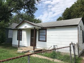 Tulsa house for rent - the front of a white house with a porch and a fence