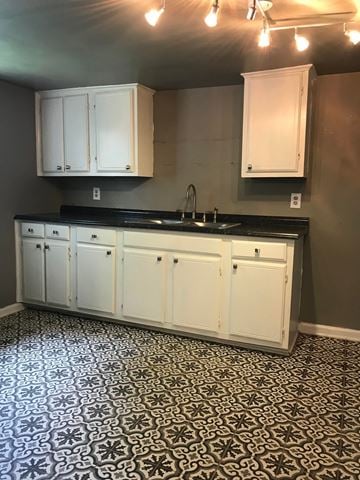 Tulsa house for rent - a kitchen with white cabinets and a black counter top