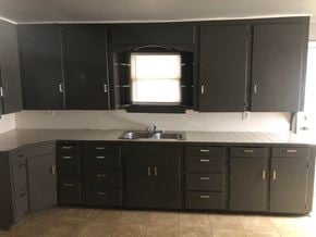 Tulsa house for rent - an empty kitchen with black cabinets and a sink