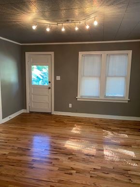 Tulsa house for rent - an empty living room with wooden floors and a white door
