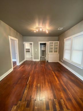Tulsa house for rent - an empty living room with wooden floors and windows