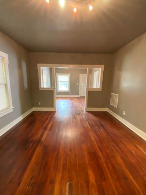 Tulsa house for rent - an empty living room with wooden floors and grey walls