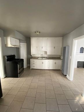 Tulsa house for rent - an empty kitchen with white cabinets and tiled floors